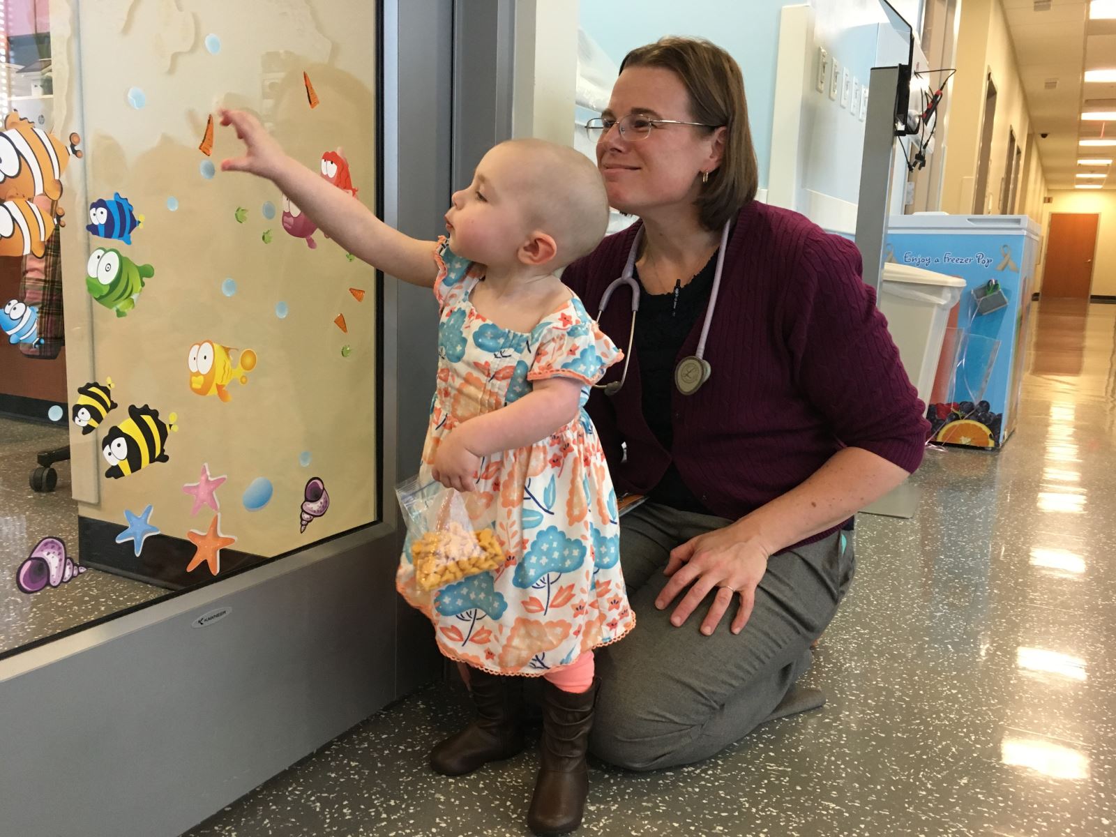 Doctor and little girl look at stickers in hematology and oncology clinic